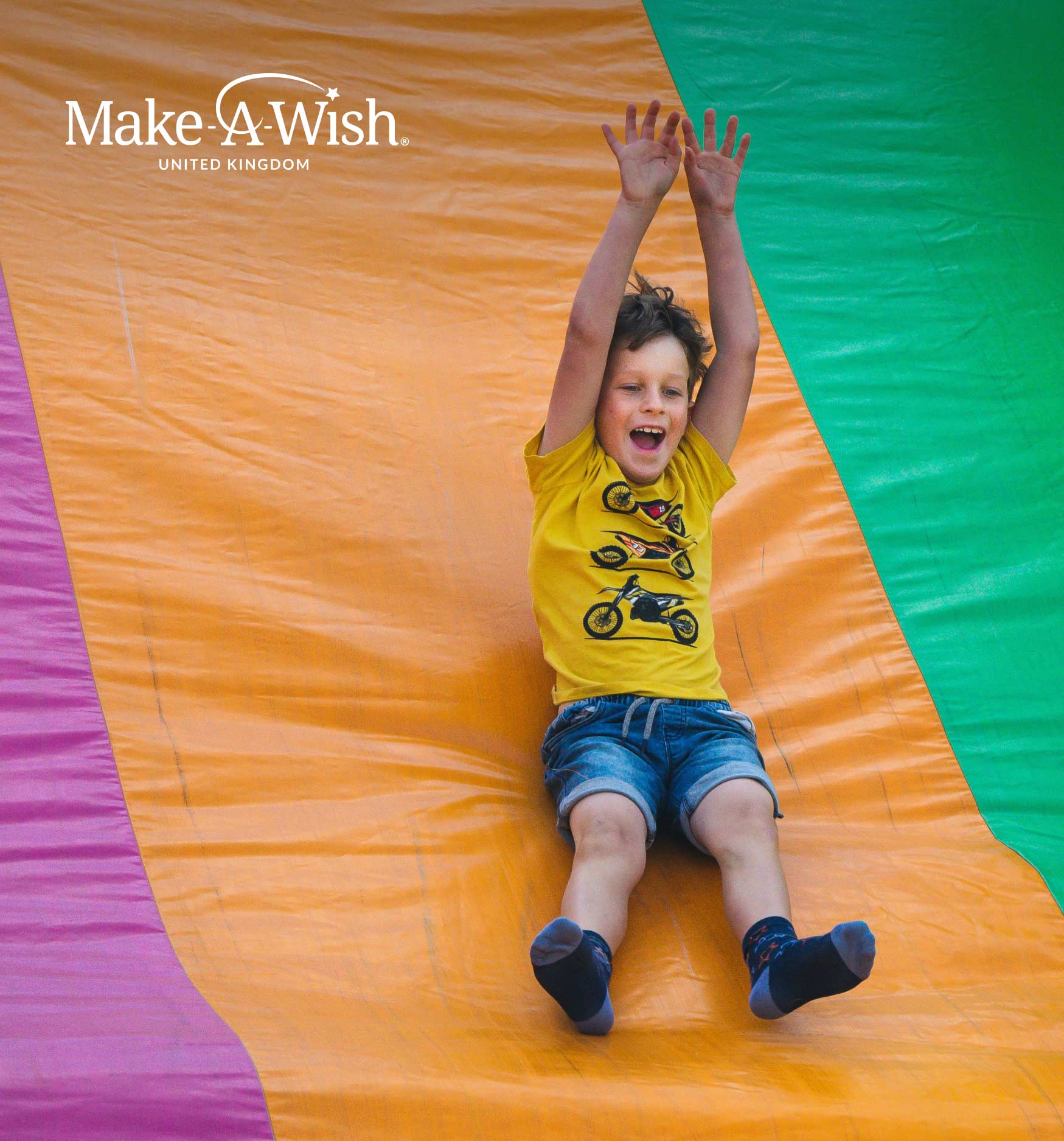 Happy child going down colourful slide.